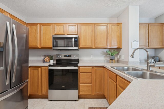 kitchen with appliances with stainless steel finishes, sink, and a textured ceiling