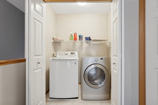 laundry room featuring light tile patterned floors, a textured ceiling, and washer and clothes dryer