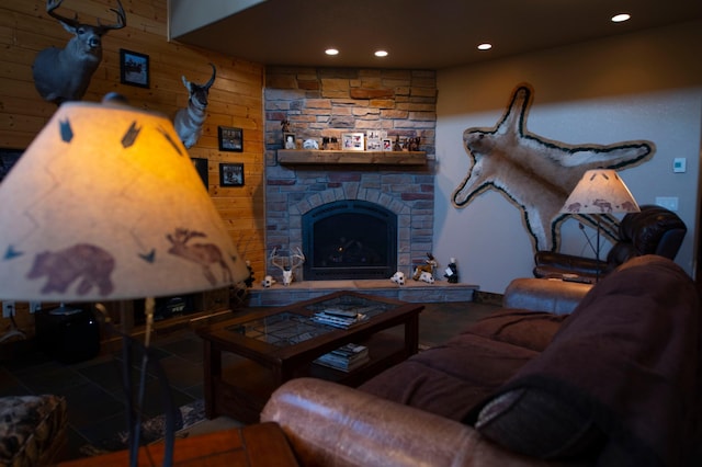 living room featuring tile patterned flooring, a stone fireplace, and wooden walls