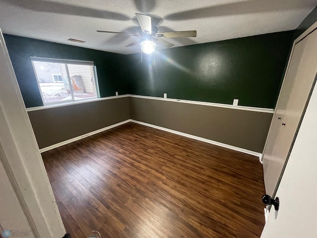 empty room with a textured ceiling, dark hardwood / wood-style floors, and ceiling fan