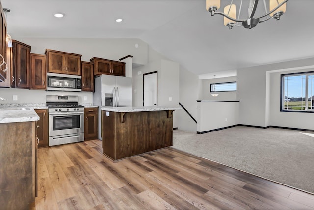 kitchen with a chandelier, pendant lighting, a kitchen bar, a kitchen island, and appliances with stainless steel finishes