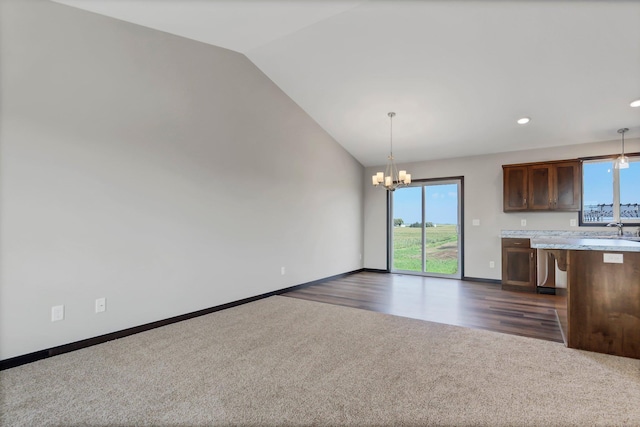 kitchen with dark colored carpet, a wealth of natural light, a chandelier, and hanging light fixtures