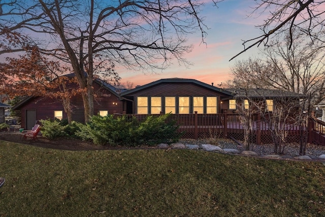 back house at dusk with a yard and a deck