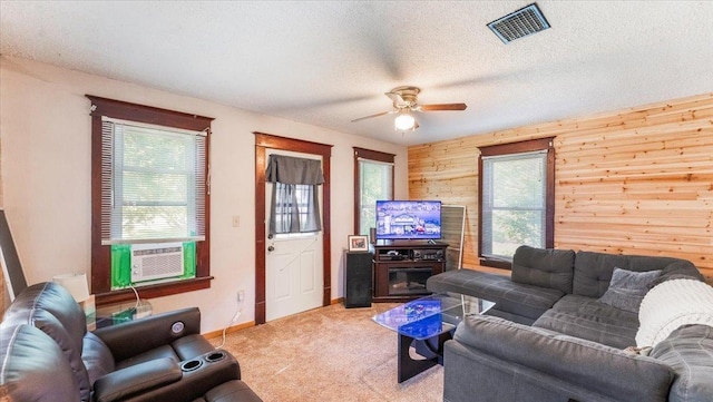 205 Broadway St SE, Isanti, MN 55040 - carpeted living room featuring ceiling fan, wood walls, a textured ceiling, and cooling unit