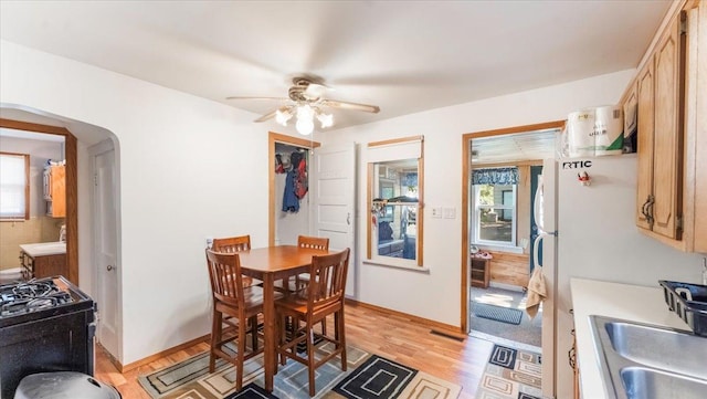 205 Broadway St SE, Isanti, MN 55040 - dining area with arched walkways, a ceiling fan, and light wood-style floors