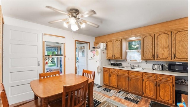 205 Broadway St SE, Isanti, MN 55040 - kitchen with freestanding refrigerator, black microwave, light countertops, and brown cabinetry