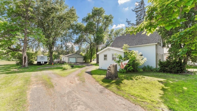 205 Broadway St SE, Isanti, MN 55040 - view of front of house featuring a garage, driveway, a front lawn, an outbuilding, and a shingled roof