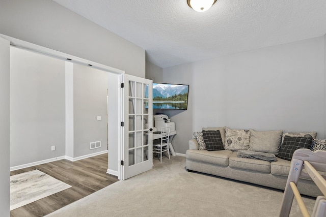 living room with hardwood / wood-style floors, a textured ceiling, and french doors