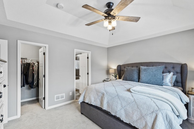 bedroom featuring a closet, a walk in closet, a tray ceiling, and ceiling fan