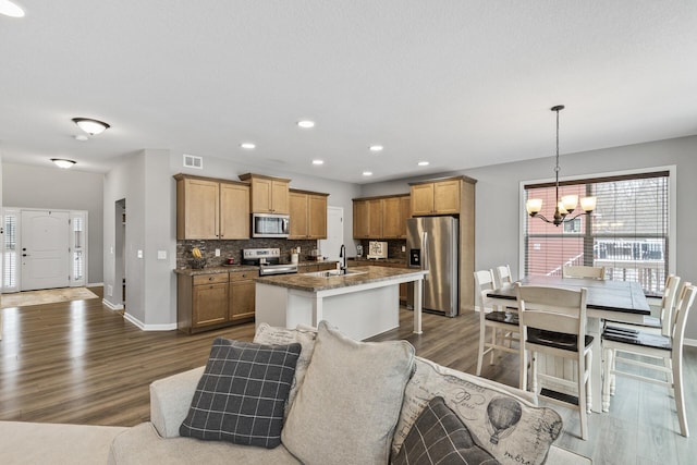 kitchen featuring hanging light fixtures, sink, an island with sink, stainless steel appliances, and a chandelier