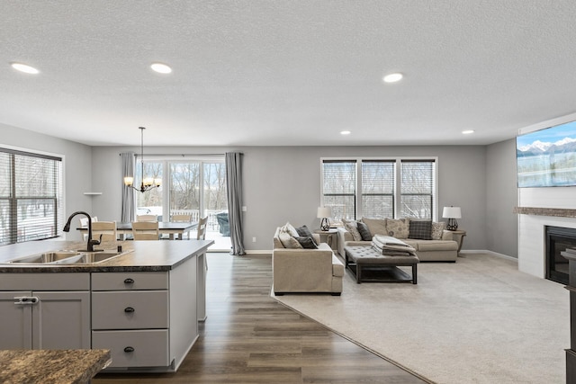 living room with a textured ceiling, dark hardwood / wood-style floors, sink, and a notable chandelier