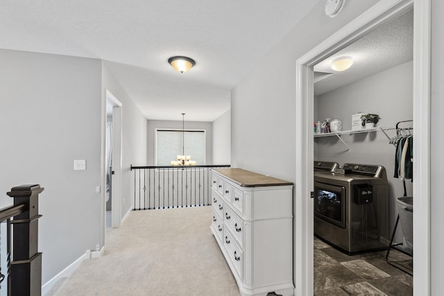 hallway with carpet, washer and dryer, a textured ceiling, and an inviting chandelier