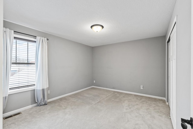 unfurnished bedroom with a textured ceiling and light carpet