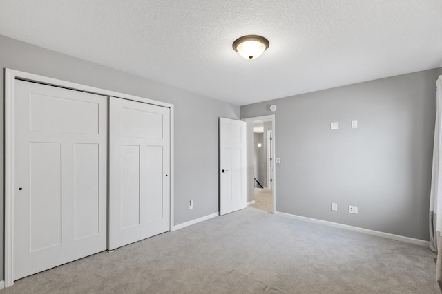 unfurnished bedroom with a textured ceiling, light carpet, and a closet