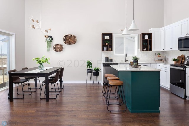 kitchen with a center island, decorative light fixtures, a kitchen bar, white cabinetry, and stainless steel appliances