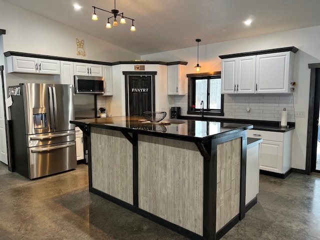 kitchen with white cabinets, hanging light fixtures, appliances with stainless steel finishes, a kitchen island, and a breakfast bar area