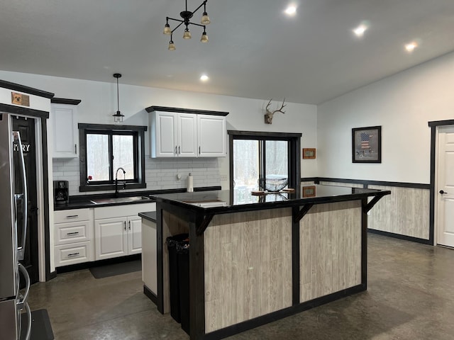 kitchen with a breakfast bar, white cabinets, a kitchen island, and hanging light fixtures