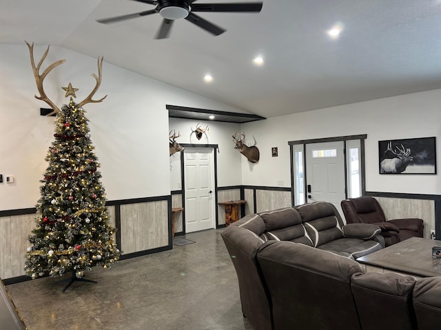 living room with ceiling fan, wood walls, concrete flooring, and vaulted ceiling