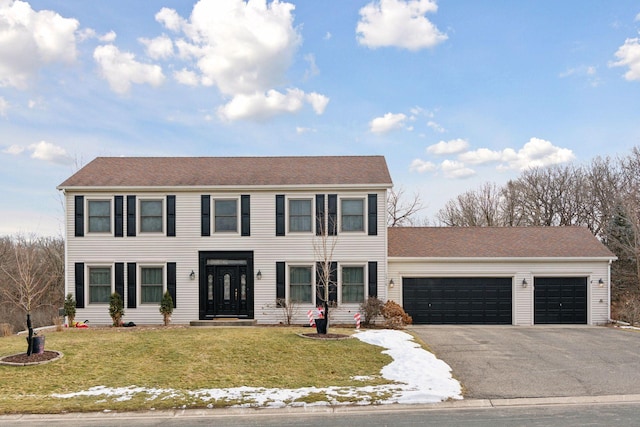 colonial house featuring a garage and a front lawn