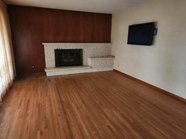 unfurnished living room featuring light wood-type flooring and a brick fireplace