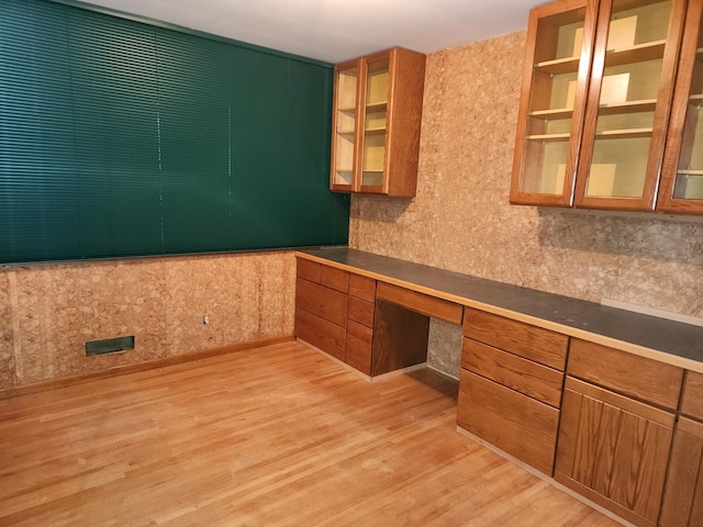 unfurnished office featuring light wood-type flooring and built in desk