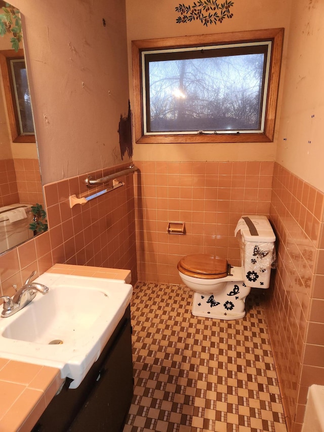 bathroom with tile patterned flooring, vanity, toilet, and tile walls