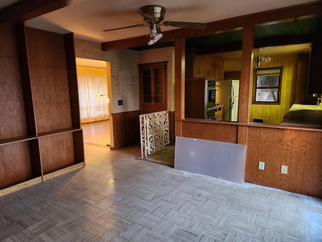 spare room with wood walls, sink, beamed ceiling, and ceiling fan with notable chandelier