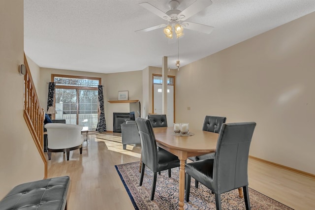 dining area with ceiling fan, light wood-type flooring, and a textured ceiling