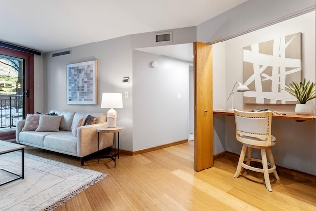 living area with wood finished floors, visible vents, and baseboards