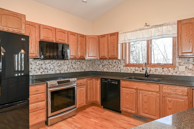 kitchen featuring black appliances, decorative backsplash, vaulted ceiling, and sink