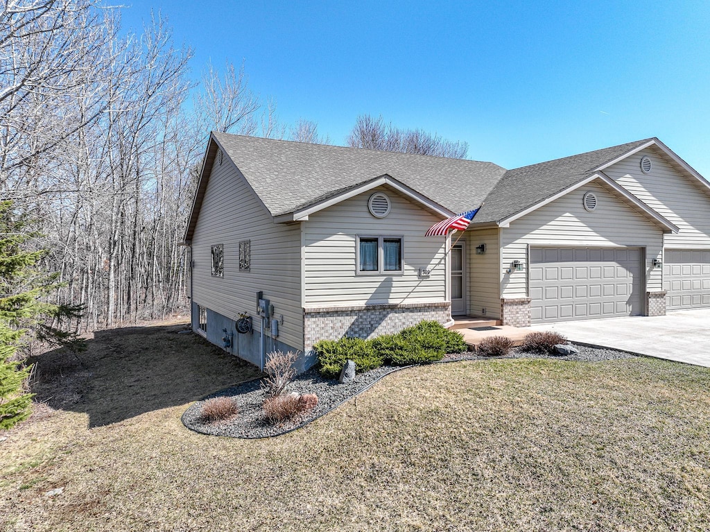 309 Hickory St, Duluth, MN 55811 - view of front of home featuring a front lawn, brick siding, roof with shingles, concrete driveway, and an attached garage