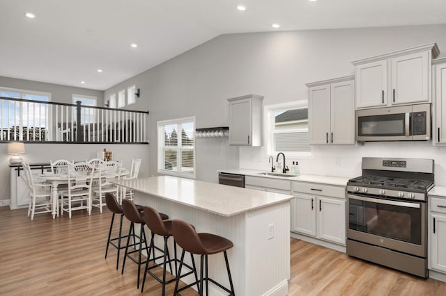 kitchen with stainless steel appliances, a breakfast bar, sink, and a kitchen island