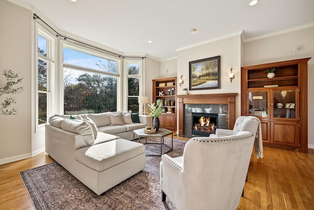 living room with a high end fireplace, wood-type flooring, and ornamental molding