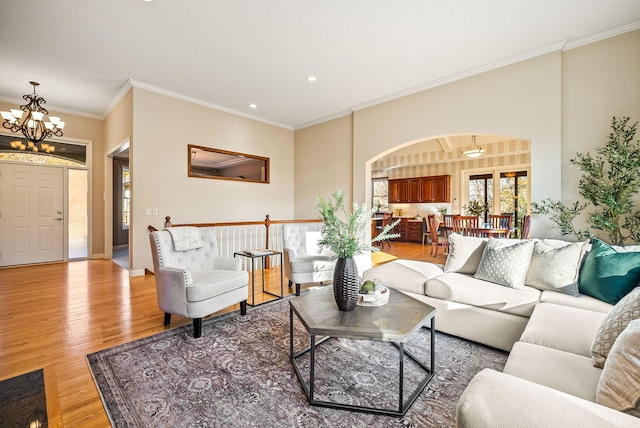 living room featuring a chandelier, light wood-type flooring, and ornamental molding