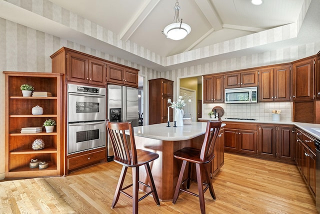 kitchen with appliances with stainless steel finishes, light hardwood / wood-style floors, a kitchen island, and a breakfast bar area