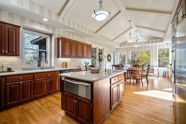 kitchen featuring plenty of natural light, lofted ceiling with beams, light wood-type flooring, decorative light fixtures, and a kitchen island