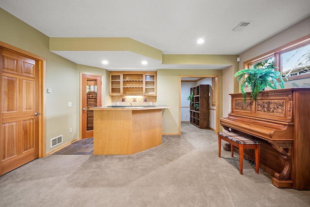 kitchen featuring carpet flooring, a breakfast bar, kitchen peninsula, and tasteful backsplash