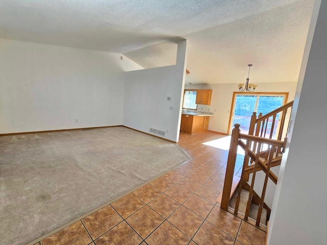 unfurnished room with a textured ceiling, carpet, a chandelier, and vaulted ceiling