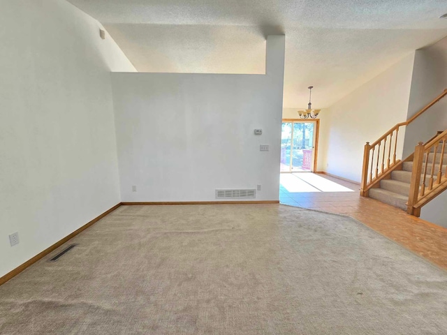 carpeted spare room featuring lofted ceiling, a textured ceiling, and an inviting chandelier