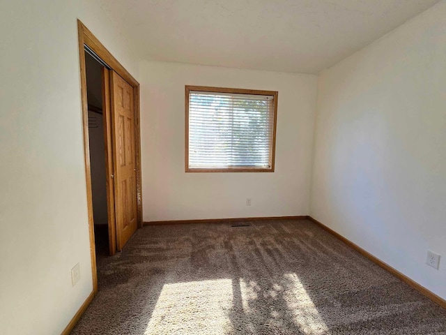 unfurnished bedroom featuring dark carpet and a closet