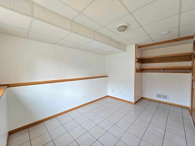 tiled spare room featuring a paneled ceiling