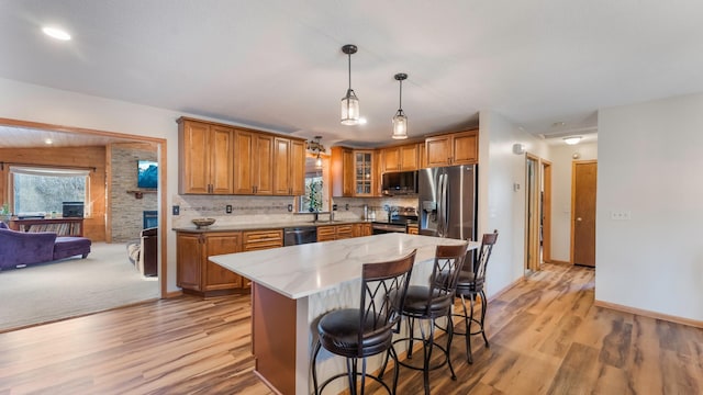 kitchen featuring backsplash, stainless steel appliances, sink, decorative light fixtures, and a kitchen island