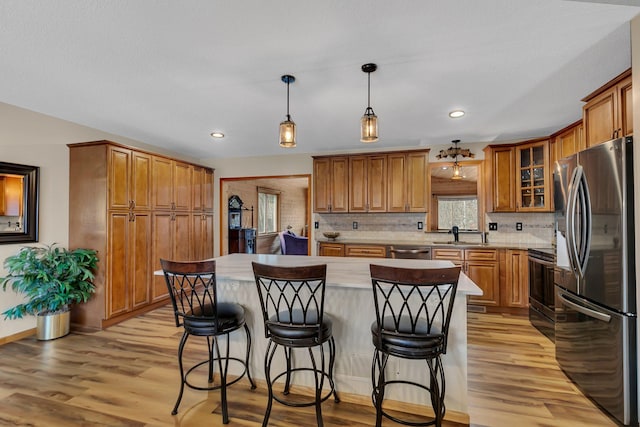 kitchen featuring a center island, stainless steel appliances, decorative light fixtures, a kitchen bar, and light wood-type flooring