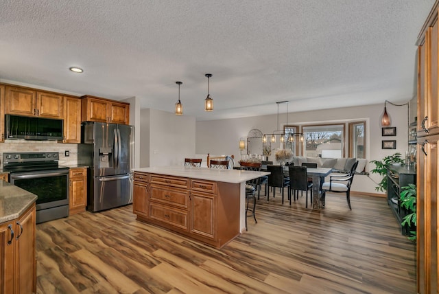 kitchen with stainless steel appliances, tasteful backsplash, hardwood / wood-style floors, a breakfast bar area, and a kitchen island