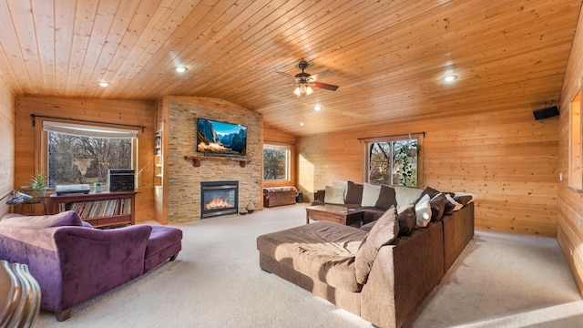 living room featuring wood ceiling, ceiling fan, wooden walls, a stone fireplace, and lofted ceiling