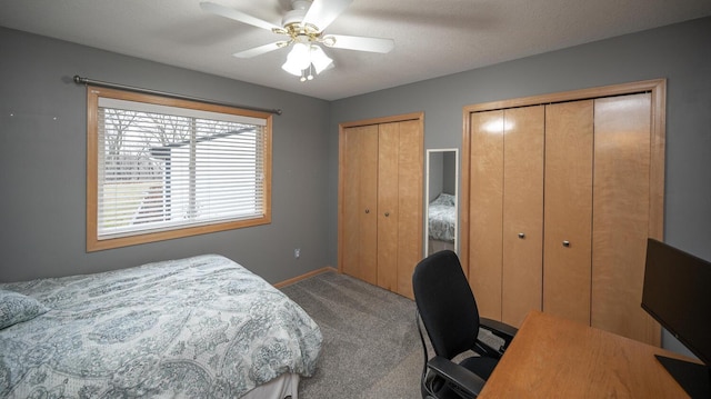 bedroom featuring carpet flooring, a textured ceiling, ceiling fan, and multiple closets