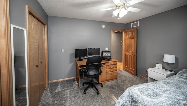 bedroom featuring ceiling fan, dark carpet, a textured ceiling, and a closet