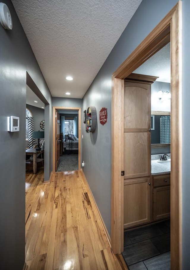 hall featuring a textured ceiling, light hardwood / wood-style floors, and sink