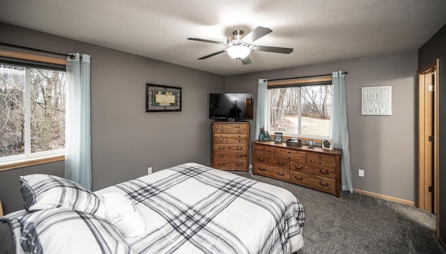 bedroom featuring ceiling fan, dark carpet, and a textured ceiling