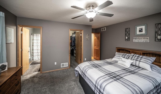 carpeted bedroom featuring a walk in closet, ceiling fan, a closet, and a textured ceiling